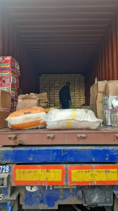 Cartons of Indomie instant noodles, pounded yam, bagged nuts and woven sacks being loaded by hand into a container in Lagos for shipping to the UK.